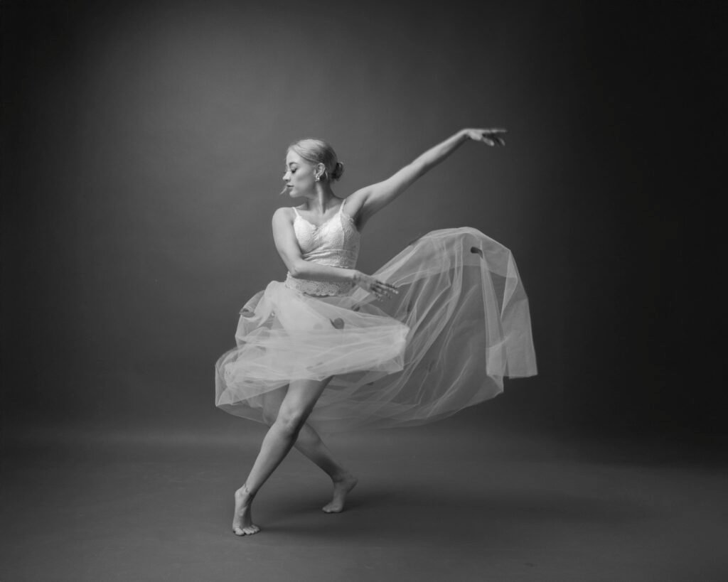 Elegant ballerina showcasing a stunning dance pose in a black and white studio setting.
