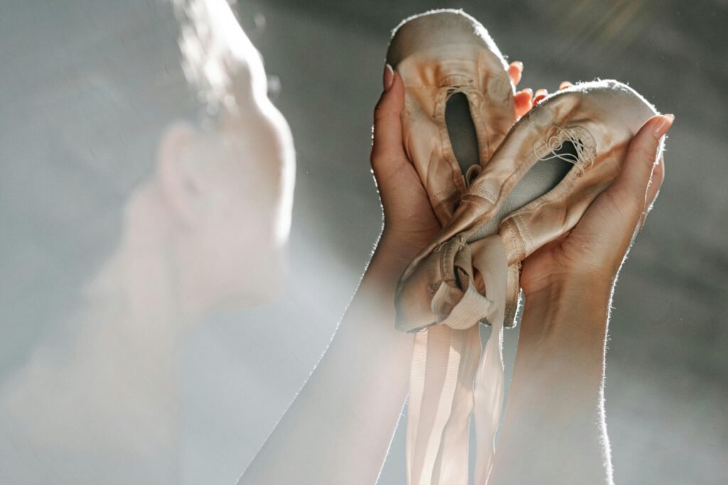 Artistic shot of a ballerina holding worn ballet shoes, highlighting grace and dedication.