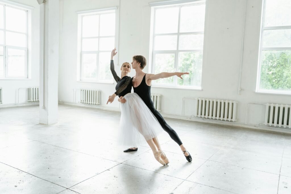 Two ballet dancers practicing in a bright studio, showcasing grace and skill.
